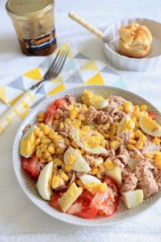 a white plate topped with meat and veggies next to a jar of jelly