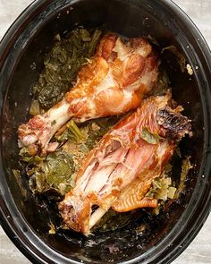 two pieces of chicken in a slow cooker with greens and seasonings on the side