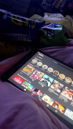 a tablet sitting on top of a bed next to a purple comforter and pillows