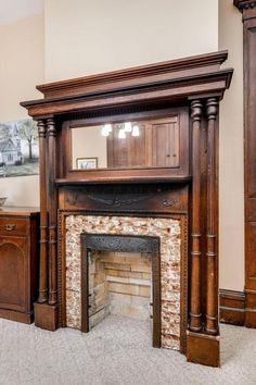 an empty living room with a fireplace in the center and wooden furniture on either side