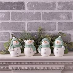 three snowmen sitting on top of a mantle