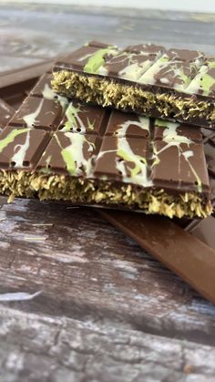 three pieces of chocolate with green sprinkles on top of each one, sitting on a wooden table