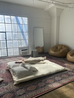 there are bean bags and pillows on the floor in an empty room with large windows