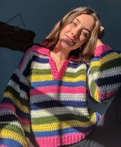 a woman is wearing a multicolored knitted sweater and posing for the camera