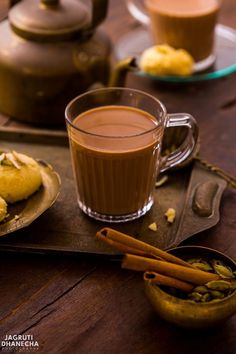 there is a cup of hot chocolate next to some cookies on a plate with cinnamon sticks