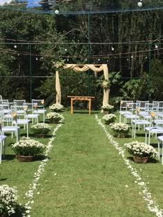 an outdoor ceremony setup with white chairs and flowers on the grass in front of it