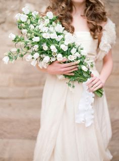 a woman holding a bouquet of white flowers