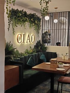 the interior of a restaurant with plants growing on the wall and tables in front of it