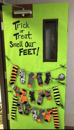 a green door decorated with halloween decorations and trick for treat smell our feet written on it