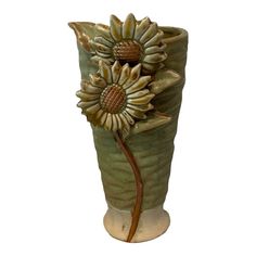 a ceramic vase with sunflowers in it on a white background and the bottom is painted green