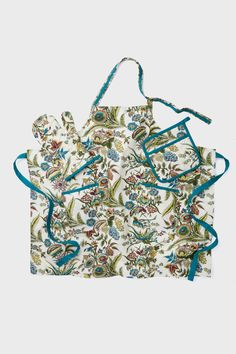 an apron with blue straps and floral print on the front, hanging from a white wall