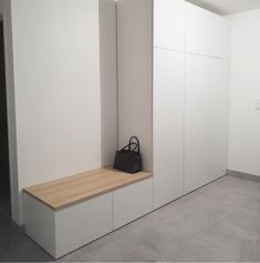 an empty room with white cupboards and a black purse on the bench in front of it