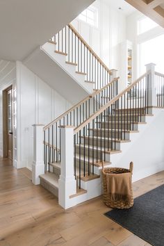 there is a basket on the floor in front of the stair case and next to the banister