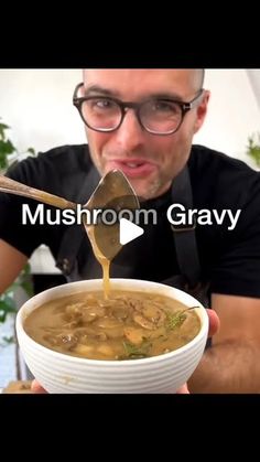 a man holding a spoon full of mushroom gravy over a bowl of soup