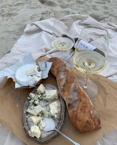 bread and cheese on a plate with two glasses of wine