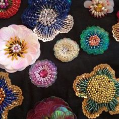 there are many different colored flowers on the black tablecloth with beadwork in them