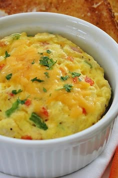 an omelet in a white dish on a plate next to bread and carrots