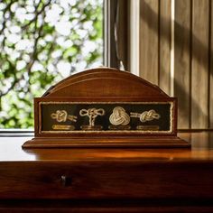 an old fashioned clock sitting on top of a wooden desk in front of a window