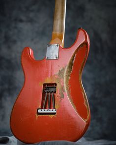 an old red electric guitar with the pick up on it's head and neck