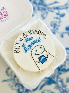 a decorated cookie in a plastic container on a blue and white tableclothed surface