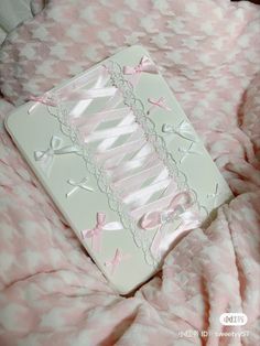 an iphone case with pink ribbon and bows on it sitting on top of a bed