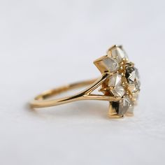 a yellow gold ring with three stones on the front and center, sitting on a white surface