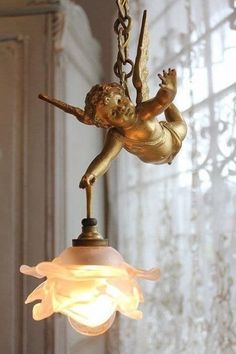 a light that is hanging from a chain with a cupid figure on the bottom