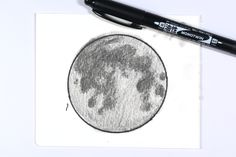 a pen is sitting next to a drawing of the moon