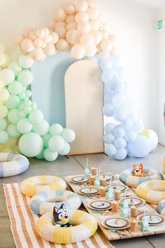 a birthday party with balloons and food on the floor, including plates and cups for desserts