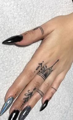 a woman's hand with black nail polish and tattoos on her left ring finger