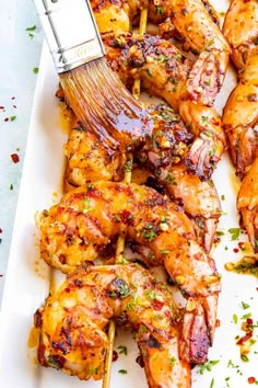 chicken skewers being grilled on a white platter with a spatula