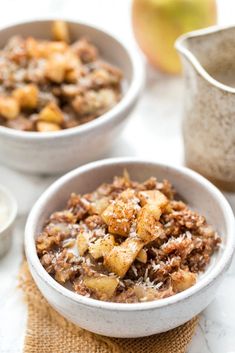 two bowls filled with food sitting on top of a table next to an apple slice