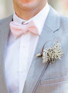 a man in a gray suit and pink bow tie wearing a boutonniere