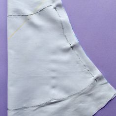 a piece of white fabric on top of a purple surface with yellow stitching and a pair of scissors