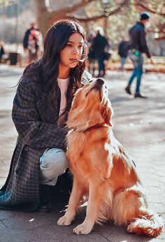 a woman kneeling down next to a brown dog