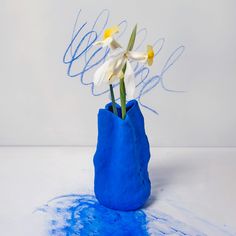 a blue vase filled with white flowers on top of a table covered in blue paint