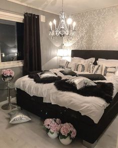 a bedroom with a bed, chandelier and flowers on the floor in front of it