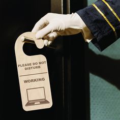 a person in white gloves is opening a door with a wooden sign that says please do not disturb working