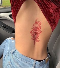 a woman with a snake tattoo on her lower back and behind her is a car