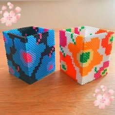 two small boxes made out of legos on a table with flowers in the background