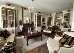 a living room filled with white furniture and lots of bookshelves next to a fire place