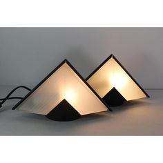 three lamps are sitting next to each other on a table, one is shaped like an upside down triangle