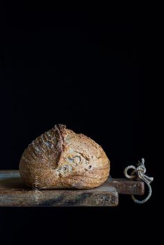 a loaf of bread sitting on top of a wooden cutting board next to a knife