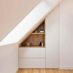 an attic bedroom with white walls and wooden flooring, built in shelving unit