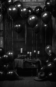 black and white photograph of balloons hanging from the ceiling in front of a table with candles on it