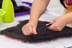 a woman is cutting fabric with scissors on the floor