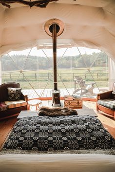 the inside of a tent with a bed, couches and a stove in it