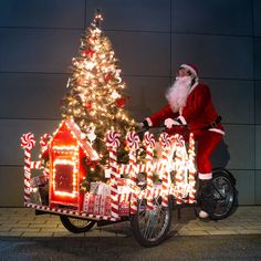 a santa clause riding on a bike next to a christmas tree