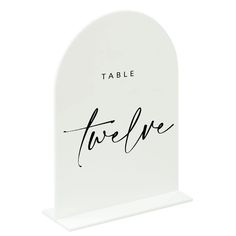 a white table sign with the word twelve written in cursive writing on it