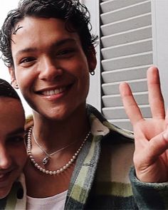 two people standing next to each other making the peace sign